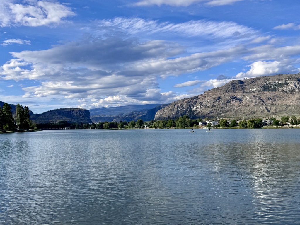 On the Lake - Paddleboarders on a calm lake with mountain peaks and valley communities