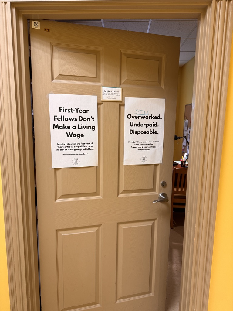 A door at King's College with two union posters reading First-Year Fellows Don't Make a Living Wage and STILL Overworked. Underpaid. Disposable.