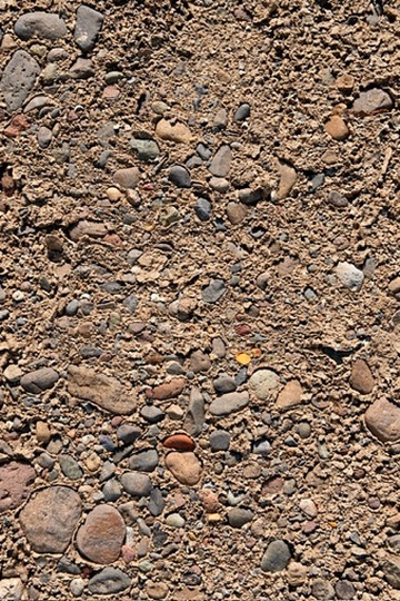 A close-up of smooth stones embedded in aggregate, many small, worn, individual stones held together in a single surface.