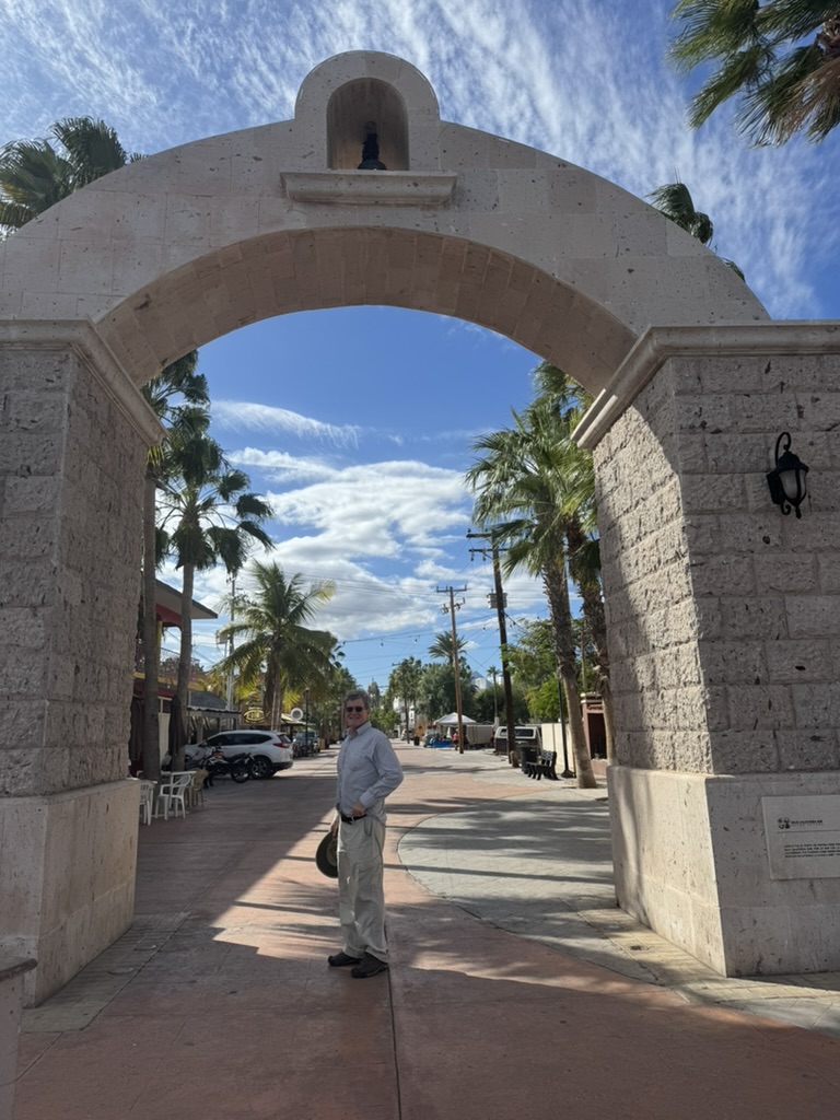Person standing under the stone mission arch in Loreto town centre