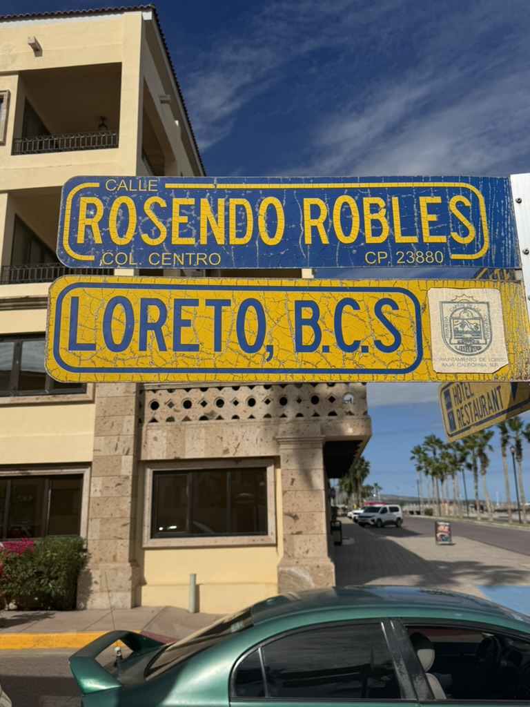 Blue and yellow Loreto, B.C.S. street sign on a sunny day